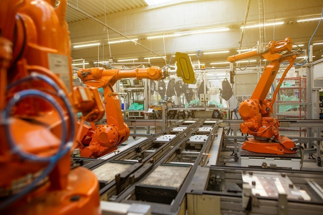 Orange industrirobotar arbetar vid transportbanor i en fabriksmiljö